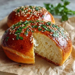 A close-up shot of a Keto Burger Bun sliced horizontally, showing the airy ivory interior crumb and glossy sesame-topped crust.