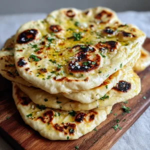 Close-up of bubbly Homemade Naan Bread with shimmering melted butter and minced garlic garnish.