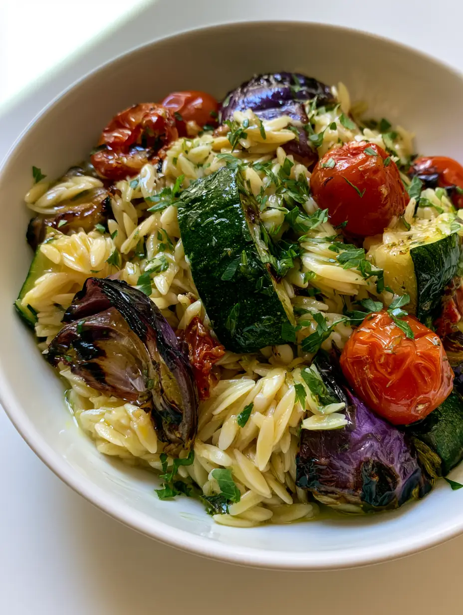 Authentic smartphone photo of Roasted Vegetable Orzo Salad showing glossy lemon dressing and charred zucchini pieces.