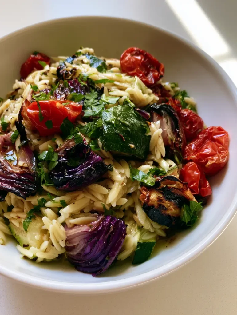 Close-up of Roasted Vegetable Orzo Salad highlighting the texture of the roasted red onions and burst tomatoes.