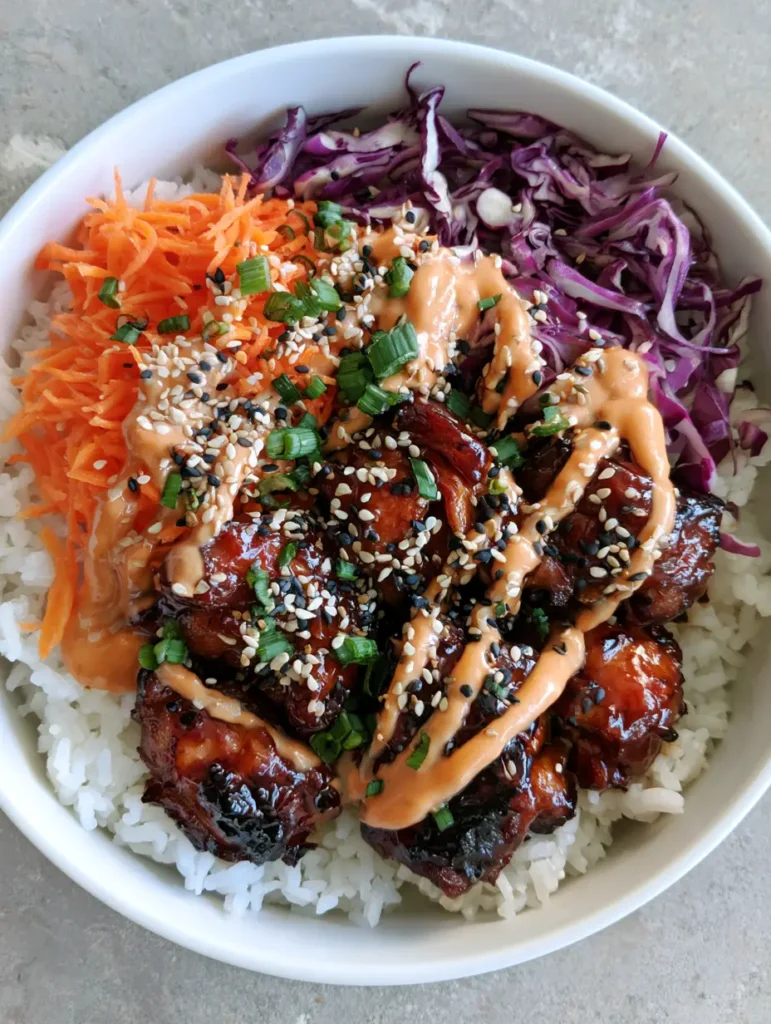 A top-down smartphone-style photo of Korean BBQ Chicken Bowls with a zig-zag of gochujang sauce.