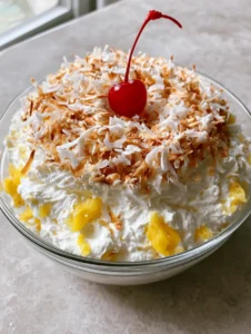 Close-up of thick, textured Hawaiian Pineapple Coconut Fluff with bright yellow pineapple bits and golden toasted coconut garnish.