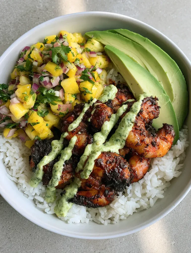 Close up of charred blackened shrimp and fanned avocado slices in a Shrimp Rice Bowl with Pineapple Salsa.