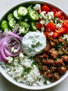 Close-up of crispy seared ground lamb crumbles and fluffy white rice in a Greek Lamb Gyro Bowl.
