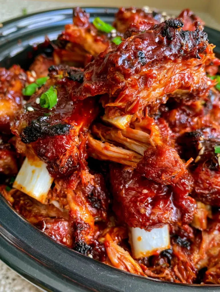Overhead shot of piled BBQ ribs with visible charred edges, scallions, and sesame seeds.