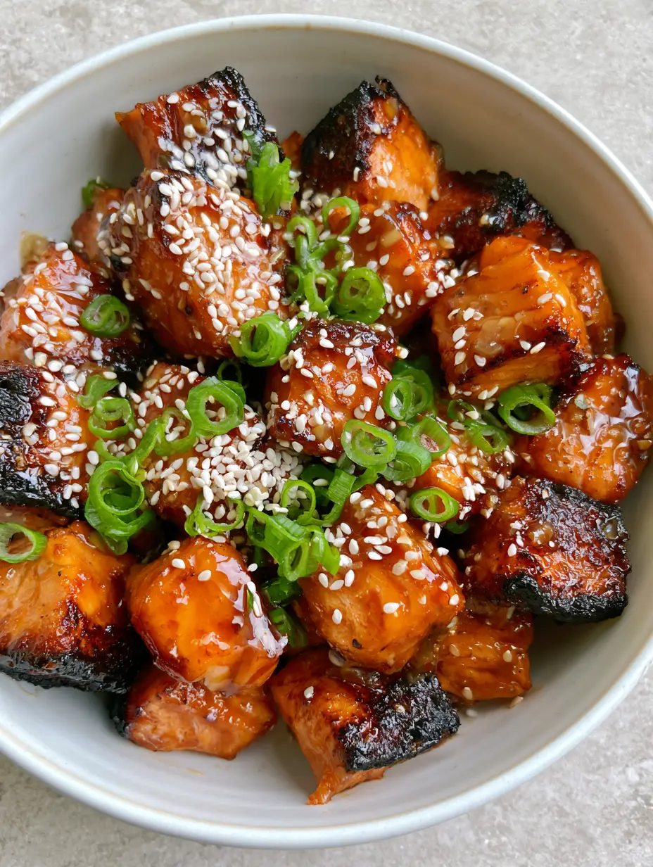 Close-up of Honey Garlic Salmon Bites showing dark caramelized crispy edges and a moist orange center.