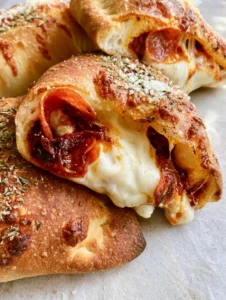 Close-up of Homemade Pizza Pockets showing charred dough bubbles and melted mozzarella cheese. (Homemade Pizza Pockets)