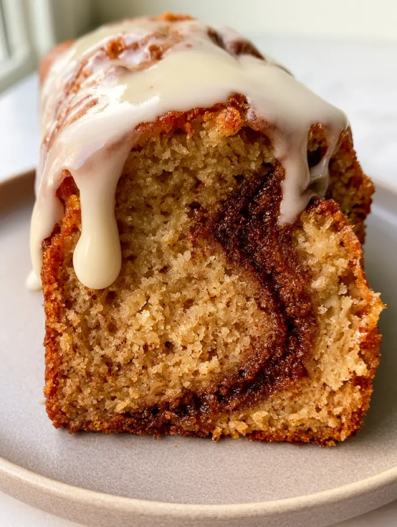 Close-up of the moist dense crumb and dark caramelized cinnamon ribbon in a slice of Cinnamon Roll Banana Bread.