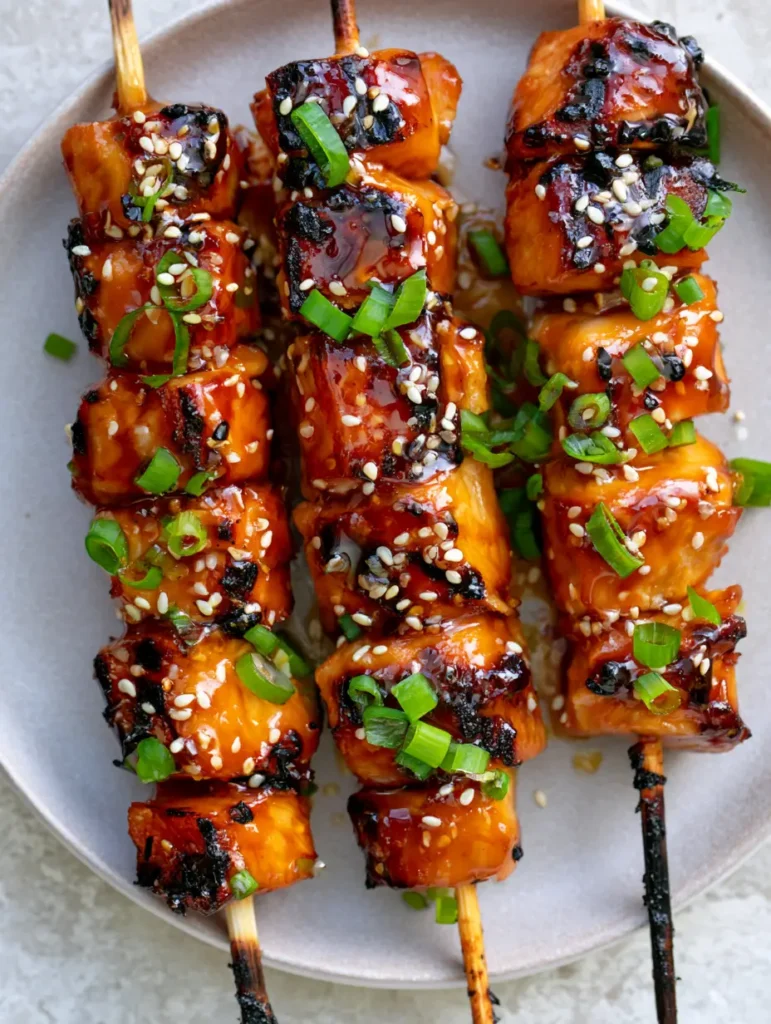 Honey Garlic Chicken Skewers: The Ultimate Sticky and Charred Grilling Recipe 1 Close-up of glossy amber-colored honey garlic glaze on seared chicken cubes with charred skewer ends.